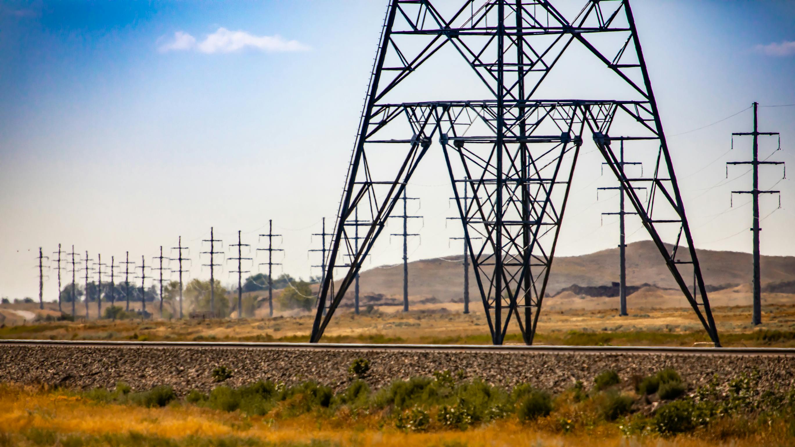 Base of electric pylon and street poles. A wide angle view showing the base of a steel lattice electric pylon by a railroad with telegraph utility poles in rural Saskatchewan, Canada