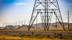 Base of electric pylon and street poles. A wide angle view showing the base of a steel lattice electric pylon by a railroad with telegraph utility poles in rural Saskatchewan, Canada Base of electric pylon and street poles. A wide angle view showing the base of a steel lattice electric pylon by a railroad with telegraph utility poles in rural Saskatchewan, Canada