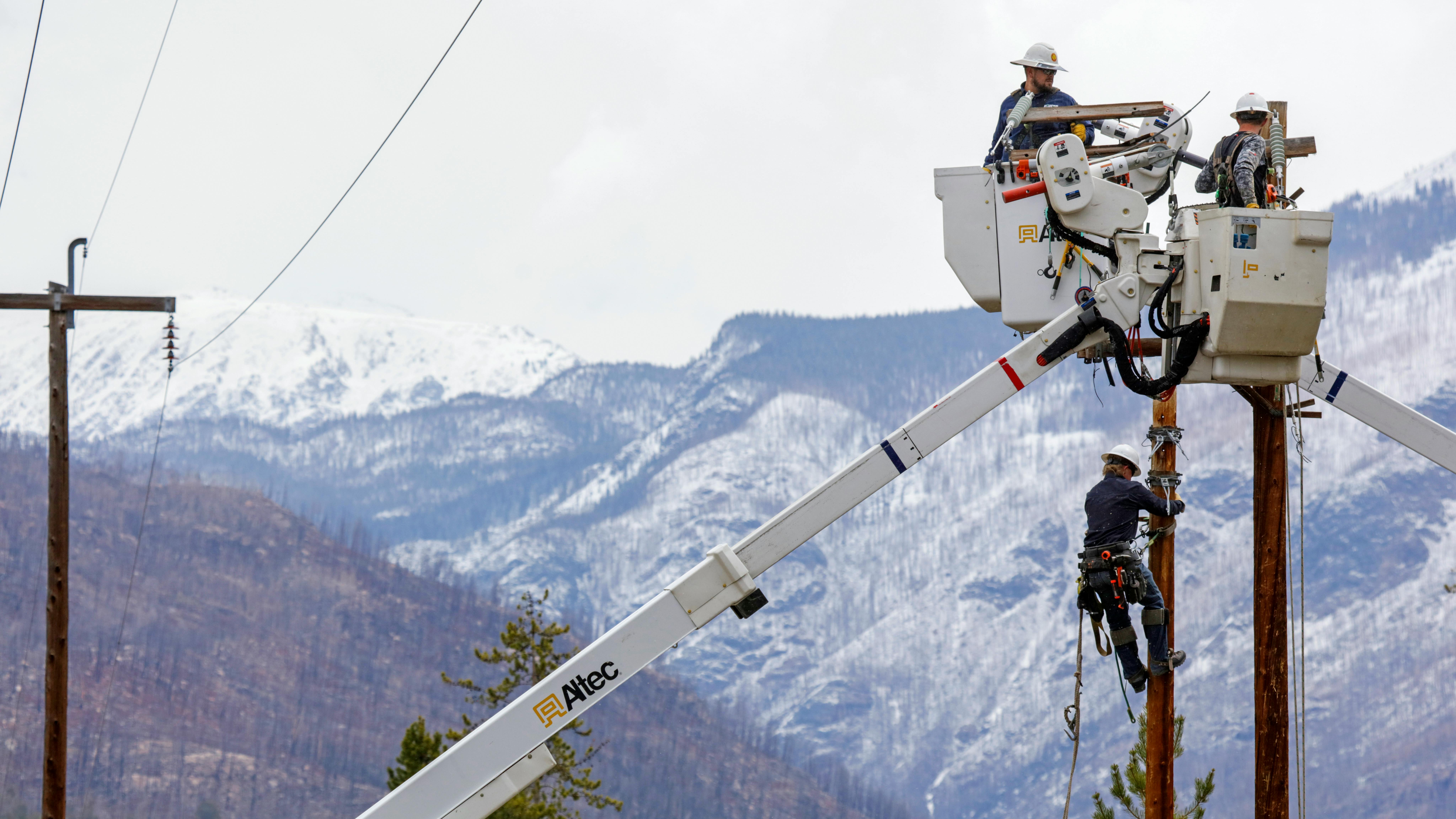 worker in bucket truck in front of mountains