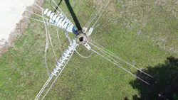 With an aerial view, damage to the top of a transmission pole is seen. With an aerial view, damage to the top of a transmission pole is seen.