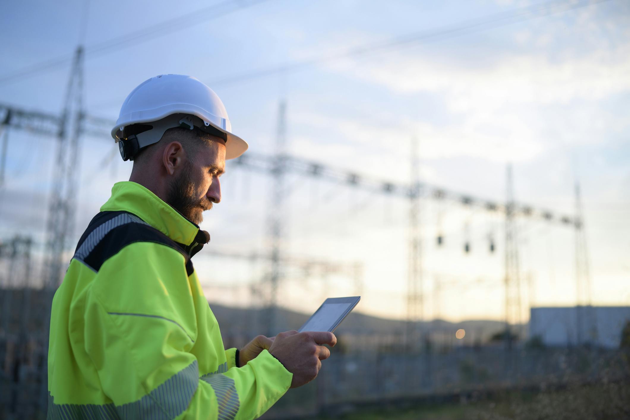 engineer in front of power lines with ipad