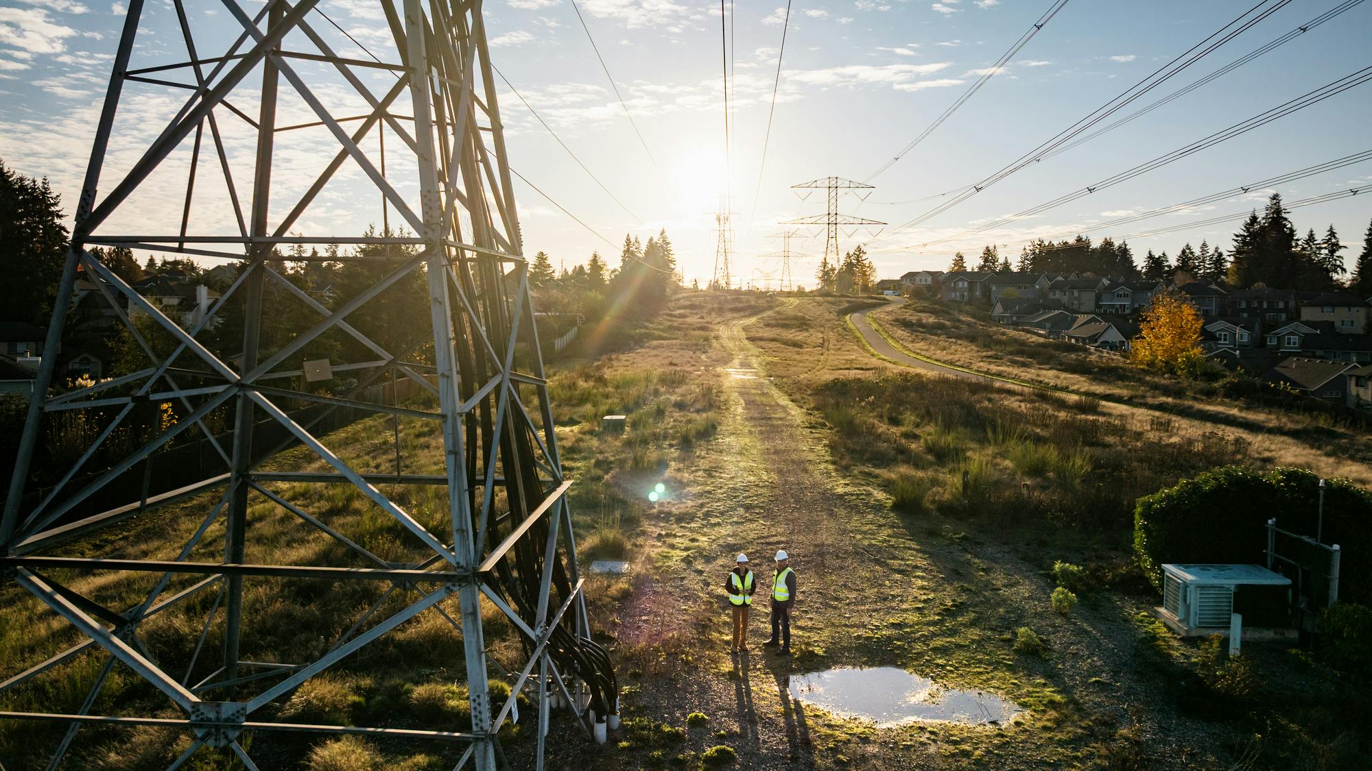 power lines by puddle with workers