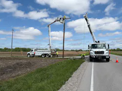 Luke Wollin, Ameren Illinois SVP of Operations and Technical Services, watches Lineworker Jodie Reinhart use a remote control to set a new power pole near Carlyle, Illinois, after high winds and severe weather knocked down several poles along a rural highway.