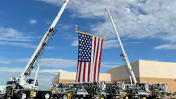 Two cranes lifting a spreader bar.