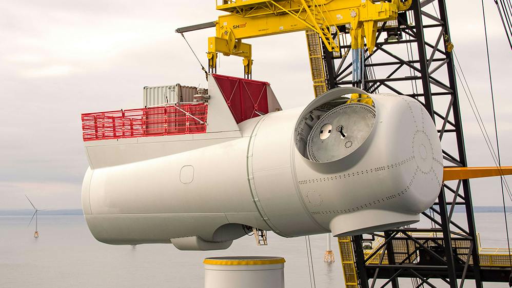 Image of a wind turbine nacelle being lifted into place by heavy-lift crane. | Credit: SSE Renewables